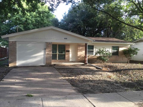 a small brick house with a driveway and a garage door